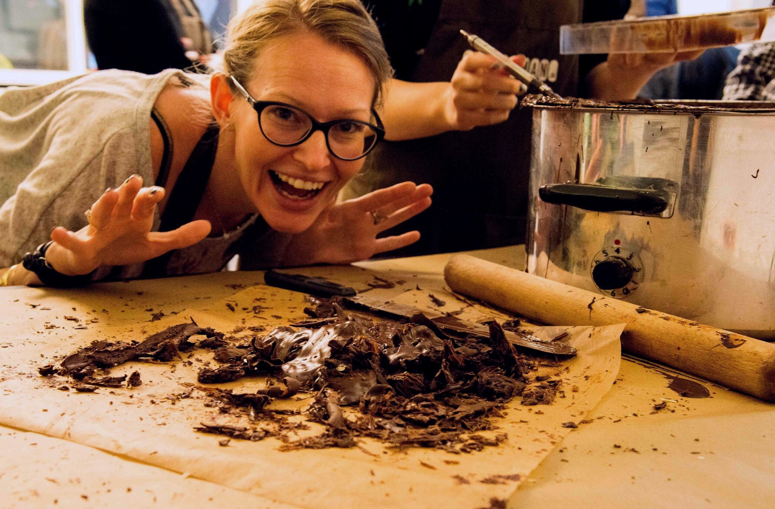 Glad kursist til chokoladekursus, der står ved chokoladerester, fra arbejde med chokolade.